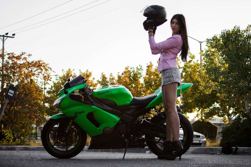 a woman standing next to the kawasaki, one of the best motorcycles for tall riders
